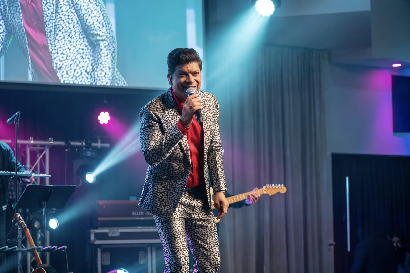 Vocalist in a patterned suit on a lit stage